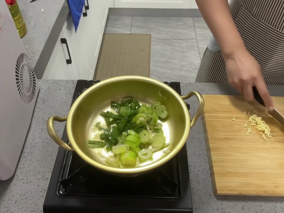 Cipollotti e aglio saltati in una pentola dorata con olio.