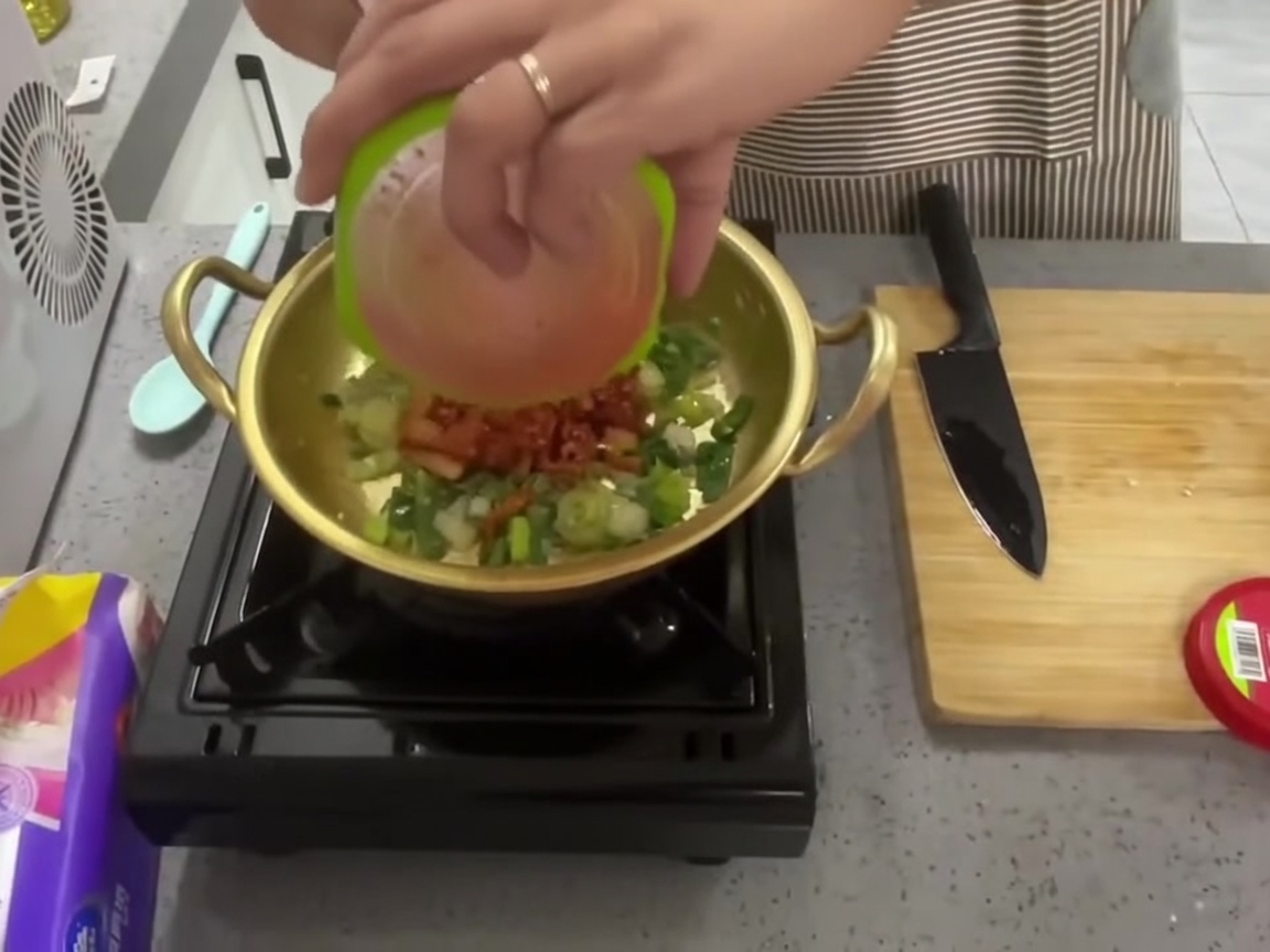 Kimchi rosso tritato versato nella pentola sopra gli aromi saltati.