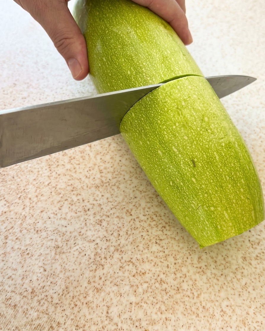 Una zucchina verde fresca tagliata a pezzi su un tagliere.