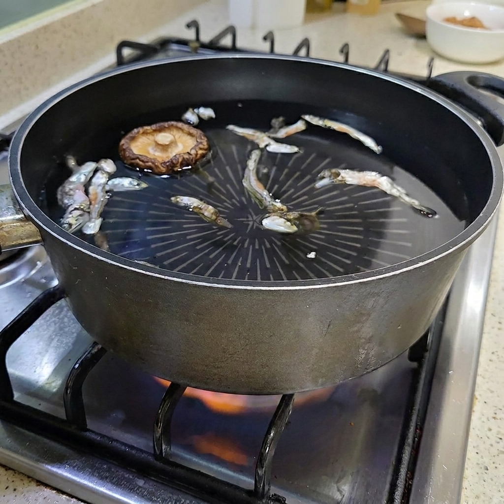 Un fungo shiitake essiccato che galleggia nella pentola dacqua con le acciughe.