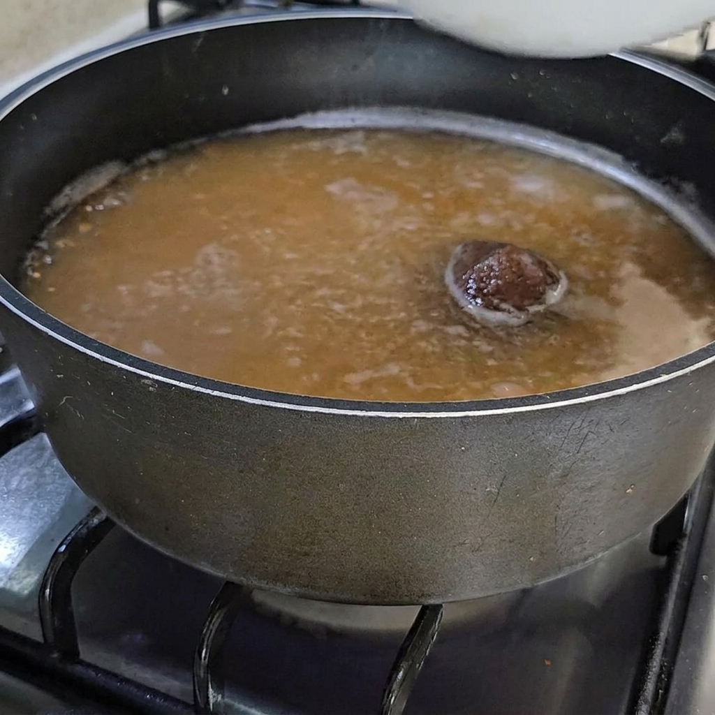 Una ciotola di ascidie arancioni fresche aggiunte al brodo di pasta di soia in ebollizione.