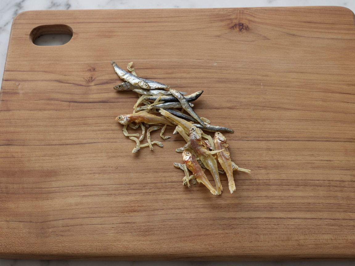 Acciughe secche su un tagliere di legno dopo essere state private di testa e interiora.