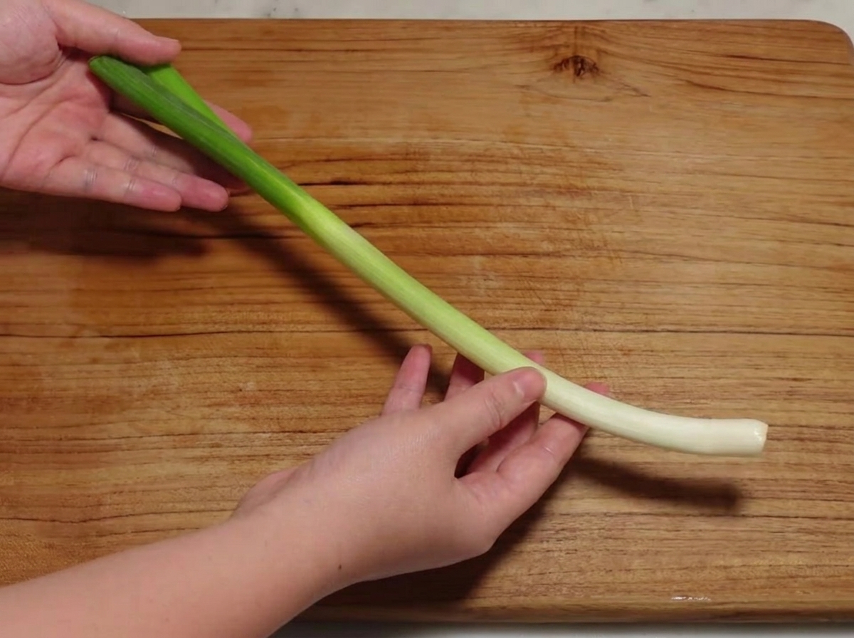 Un cipollotto tagliato a piccole sezioni su un tagliere di legno.