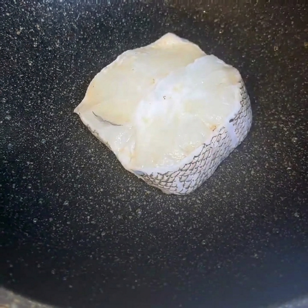 Pezzi di filetto di merluzzo puliti disposti ordinatamente allinterno di una padella scura.