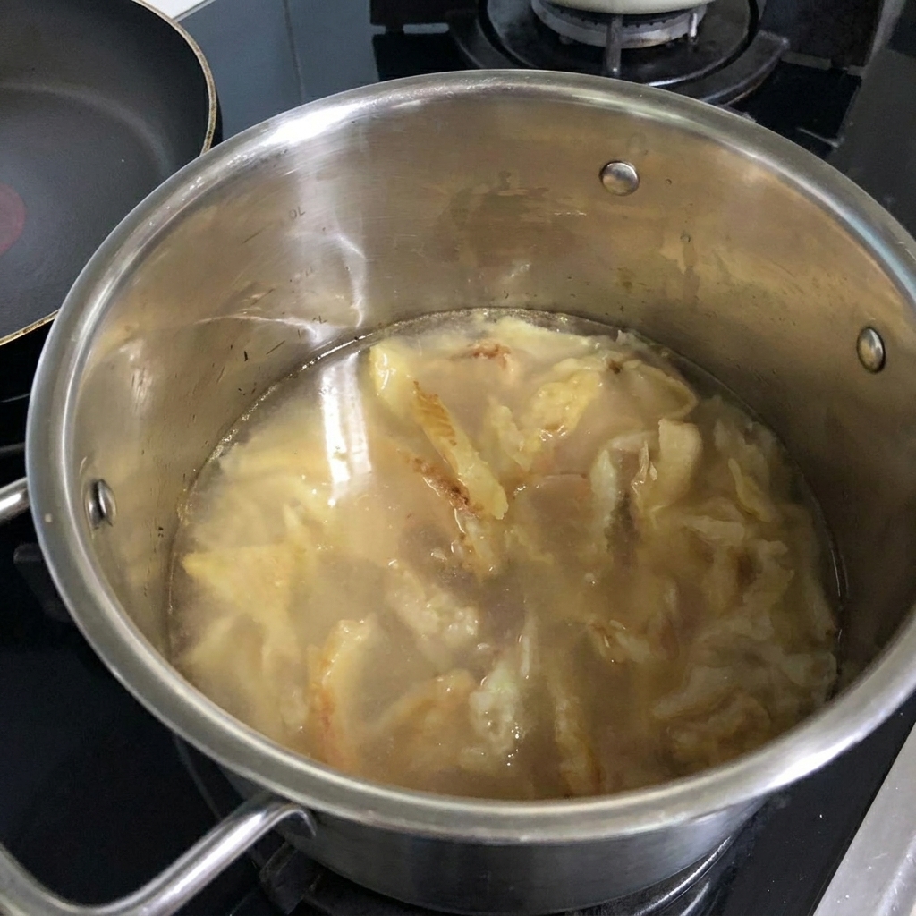 Acqua che viene versata da una bottiglia nella pentola con il pollack rosolato.