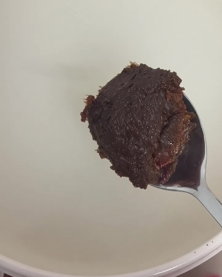 Un cucchiaio di pasta di soia marrone e pasta di peperoncino rossa mescolati nel brodo.