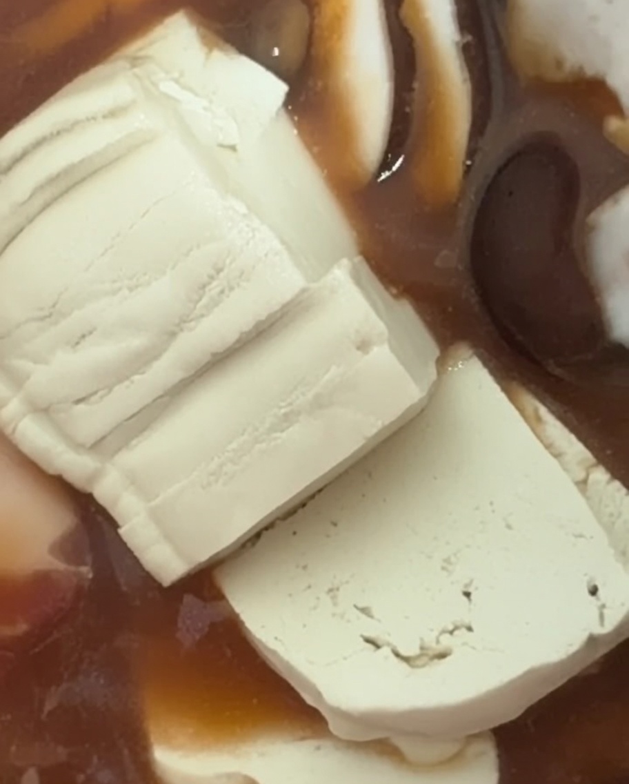 Fette di tofu bianco adagiate nello stufato.