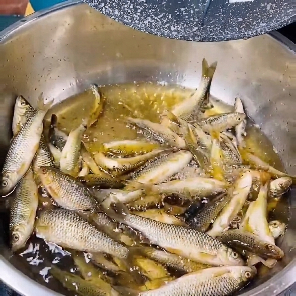 Piccoli pesci di fiume freschi risciacquati in una ciotola di metallo con acqua limpida.