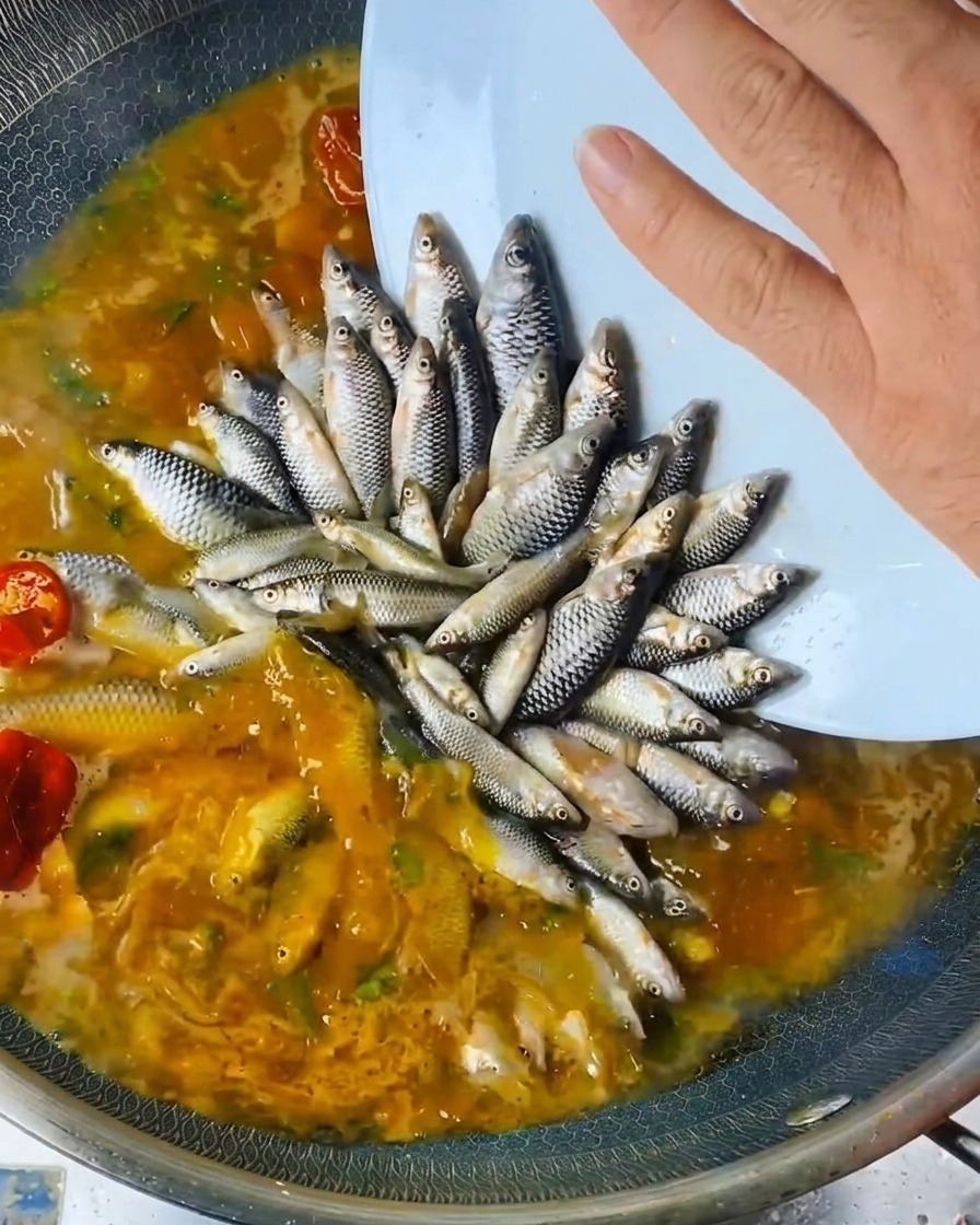 Liquido versato sopra il pesce disposto nel wok.