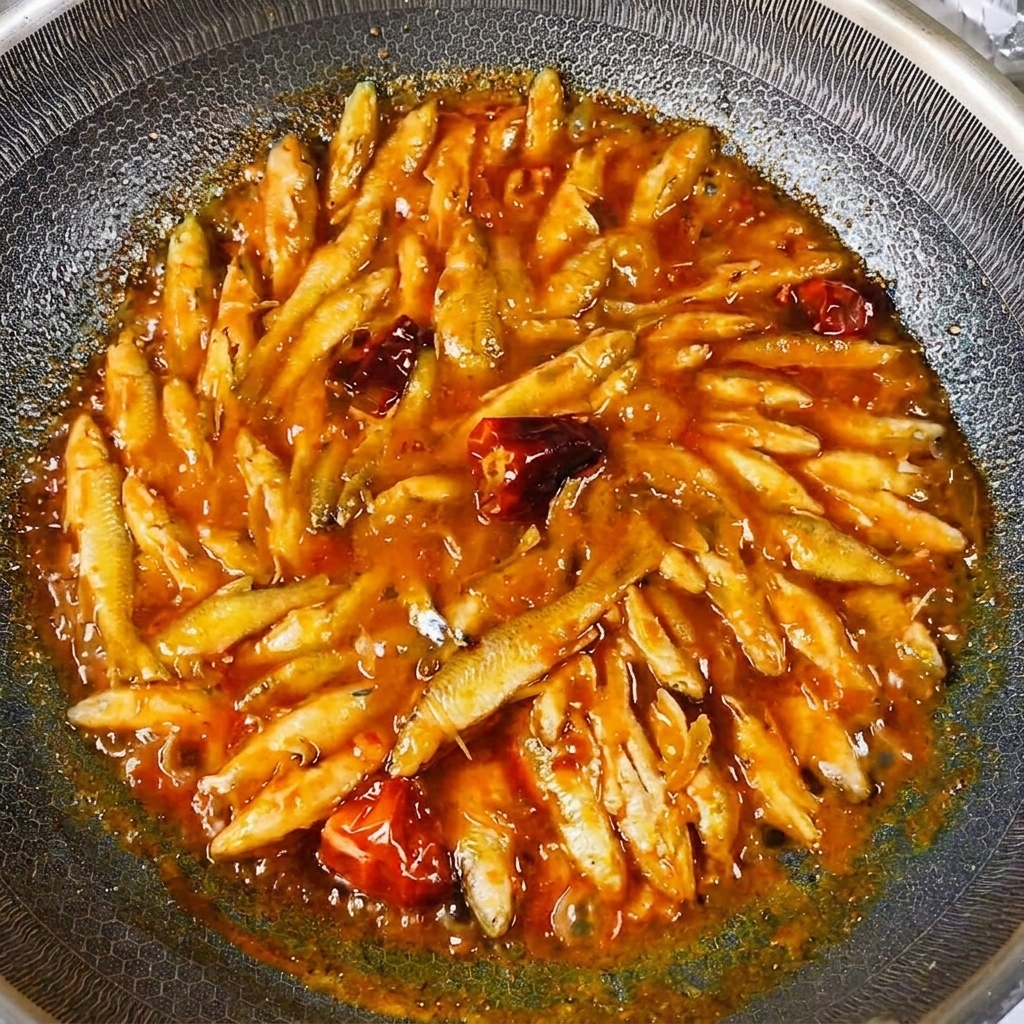Pesci cotti che luccicano con una salsa densa nel wok.