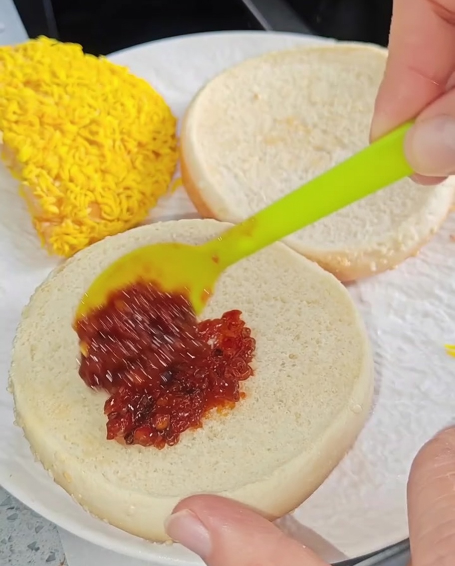 Una piccola spatola che spalma la salsa al peperoncino sulla superficie interna del pane tostato.