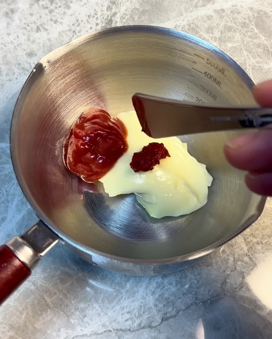 Ingredienti per la salsa mescolati in una tazza di acciaio inox.