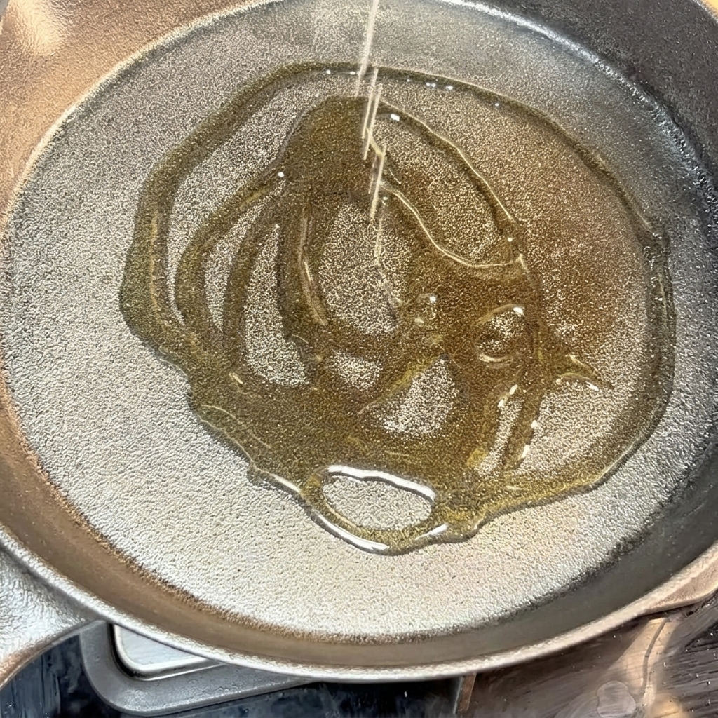 Burger di manzo che sfrigola in una padella di ghisa calda con olio.