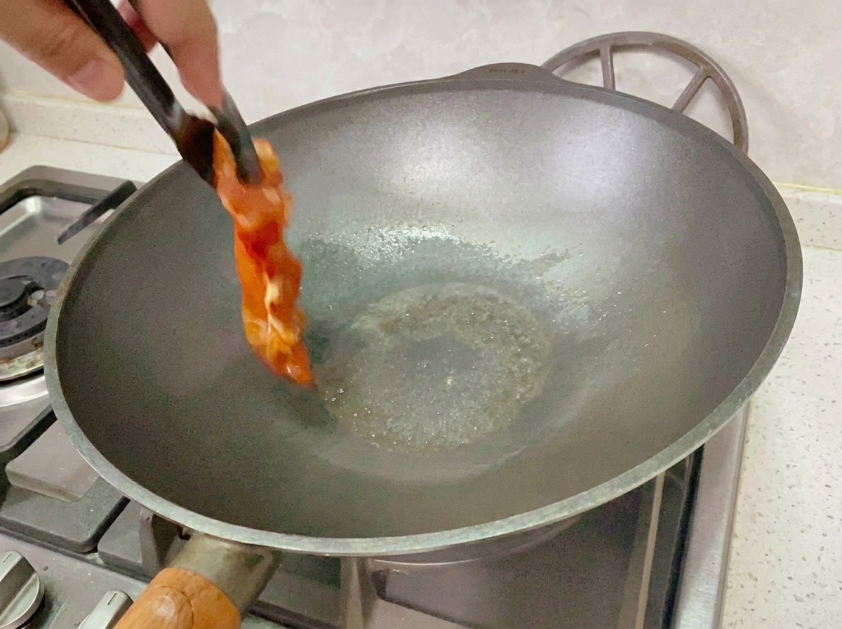 Pollo marinato che cuoce in una padella a fuoco medio-basso.