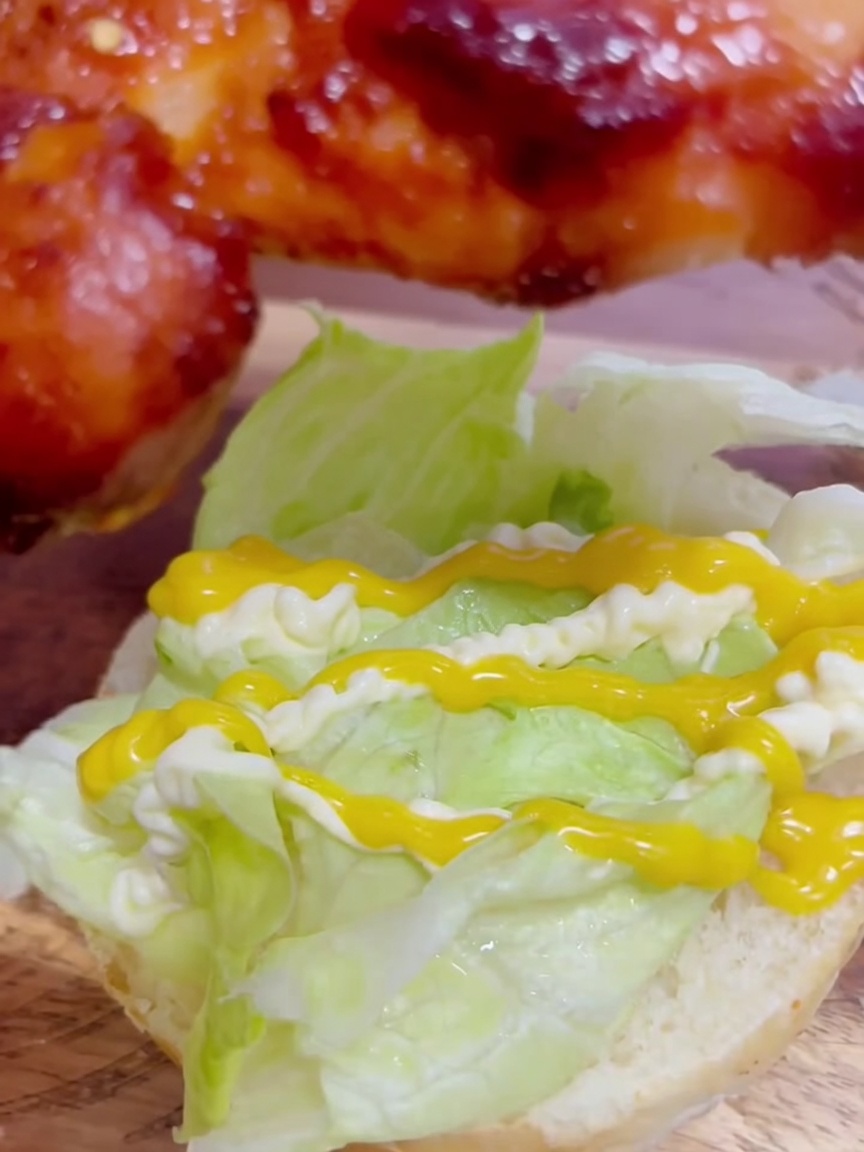 Una sovracoscia di pollo teriyaki glassata posizionata sopra la lattuga condita con salse.