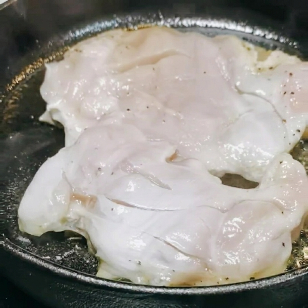 Salsa teriyaki e vino bianco versati nella padella sopra il pollo in cottura.