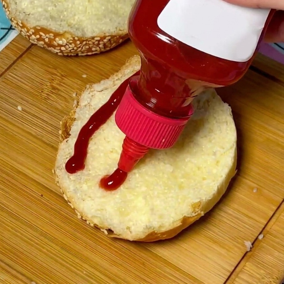 Un vortice di ketchup rosso applicato al centro di un panino tostato con semi di sesamo.