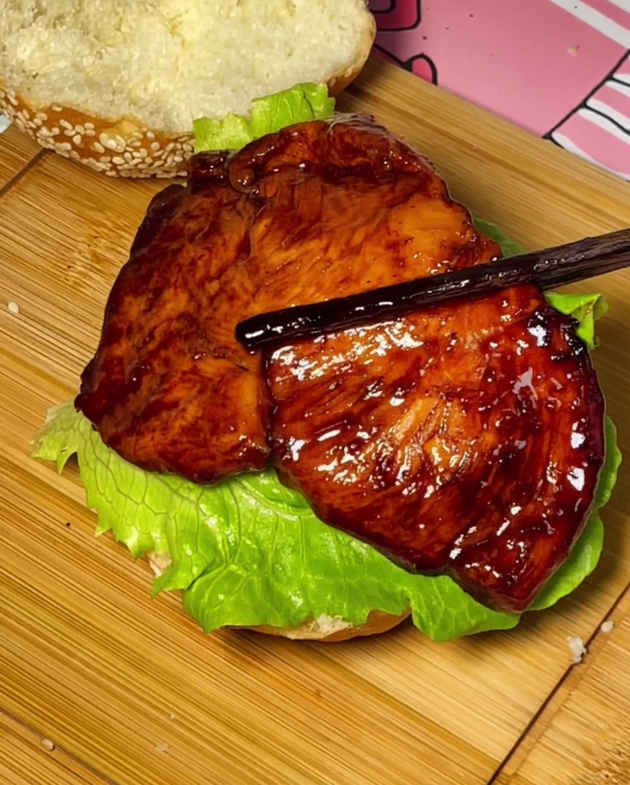 Pollo teriyaki, pomodoro e formaggio impilati sul panino da hamburger.