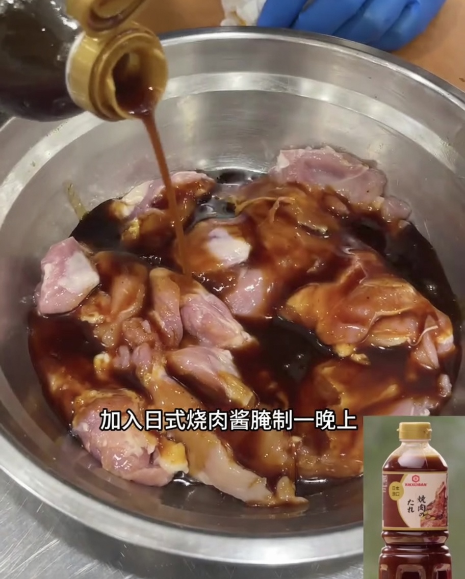 Sovracosce di pollo disossate immerse in abbondante salsa teriyaki giapponese allinterno di una ciotola in acciaio.