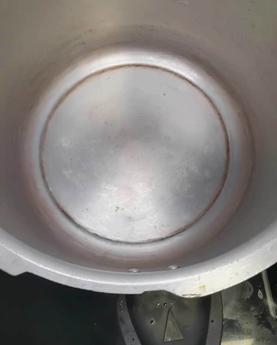 Olio di arachidi che brilla sul fondo di una pentola a pressione vuota.