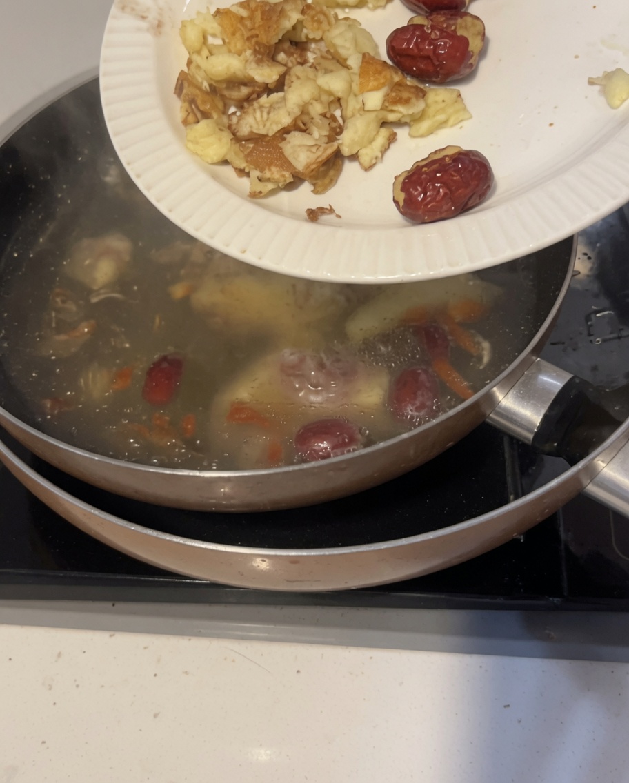 Primo piano di zenzero sabbioso pestato e datteri rossi che galleggiano in una pentola dacqua fredda.