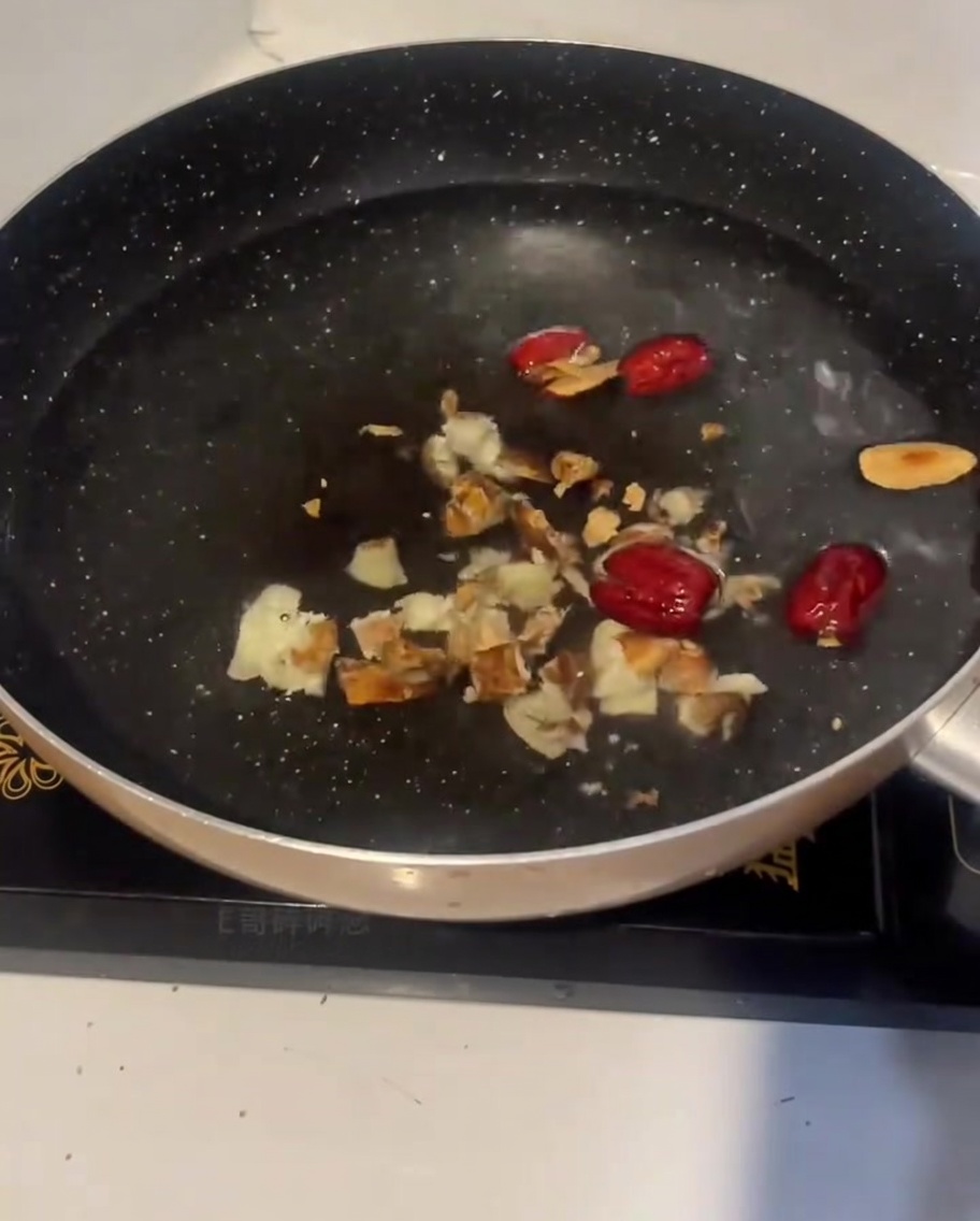 Pezzi di pollo crudo inseriti nella pentola dacqua fredda con zenzero e datteri rossi.
