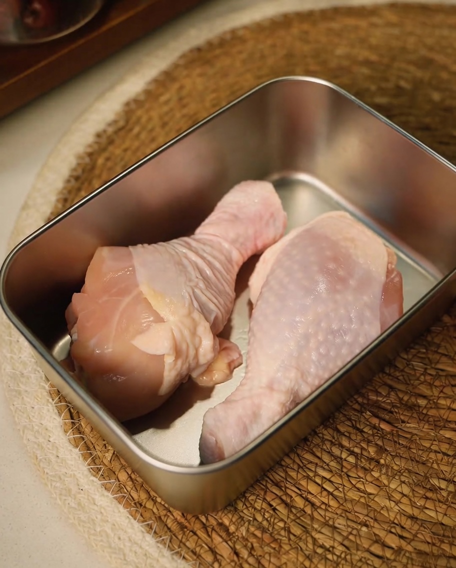 Sovracosce di pollo crude rifilate con forbici da cucina in un contenitore di metallo.