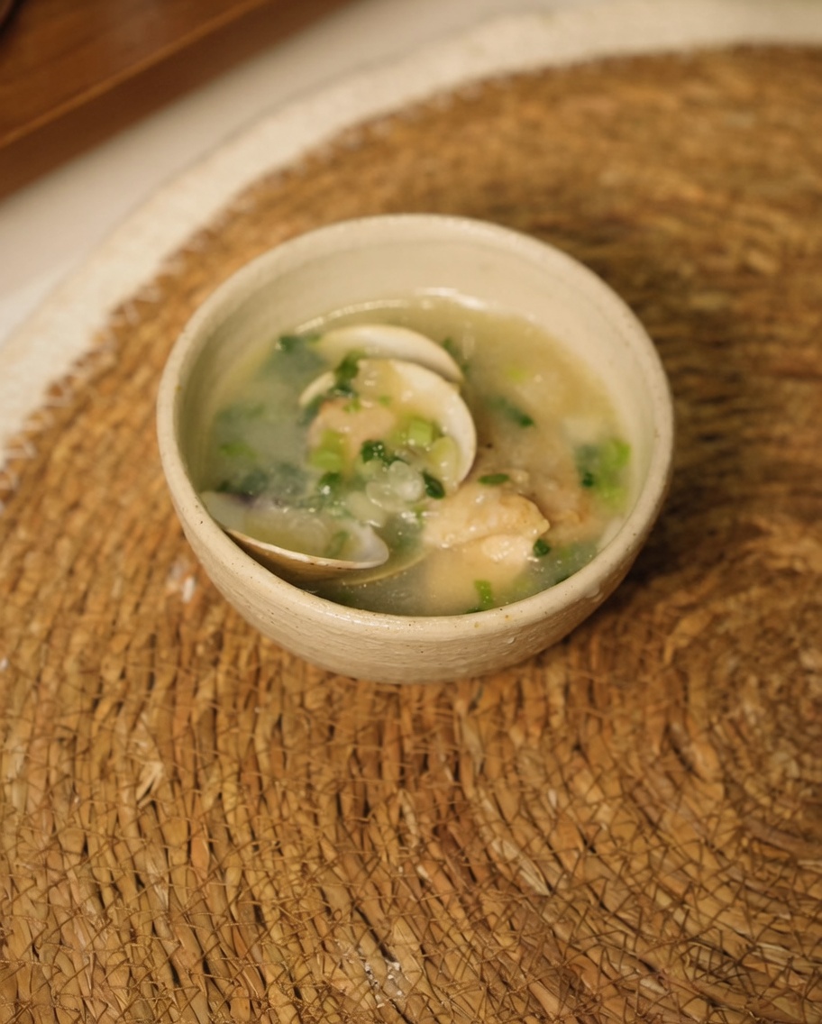 Pezzi di pollo uniti a cipolle e aglio soffritti, con acqua bollente versata nella padella.