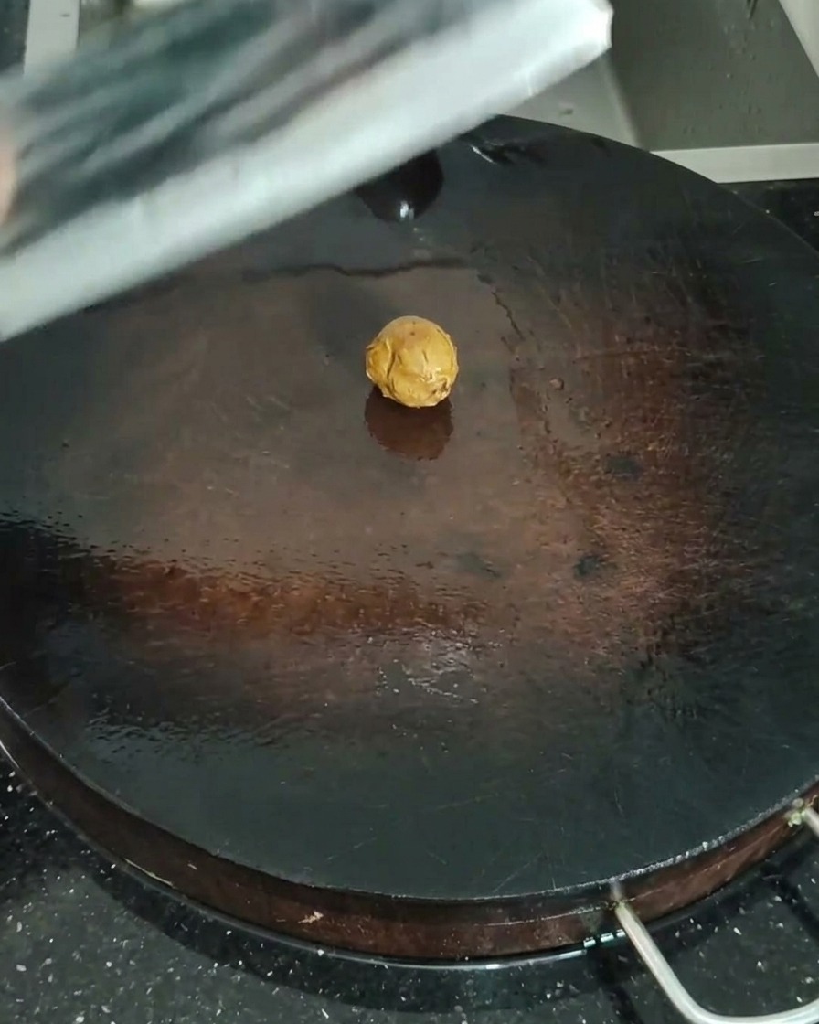 Primo piano dello zenzero sabbioso schiacciato con una mannaia su un tagliere di legno.
