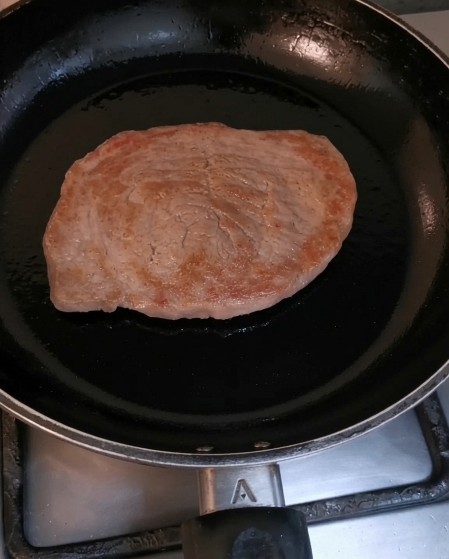 Un filetto di manzo che rosola in una padella nera rovente.