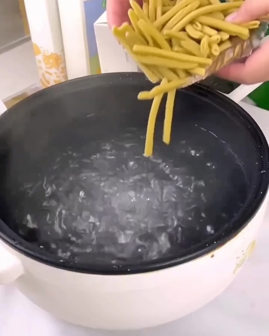 Penne di miglio secche versate in una pentola di acqua bollente.
