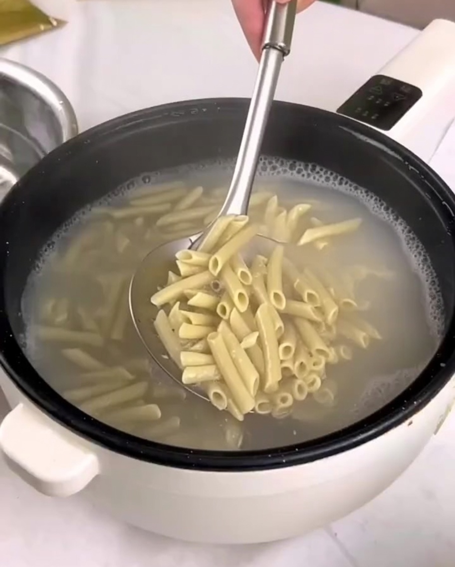 Pasta cotta trasferita dalla pentola in una ciotola di acqua fredda con una schiumarola.
