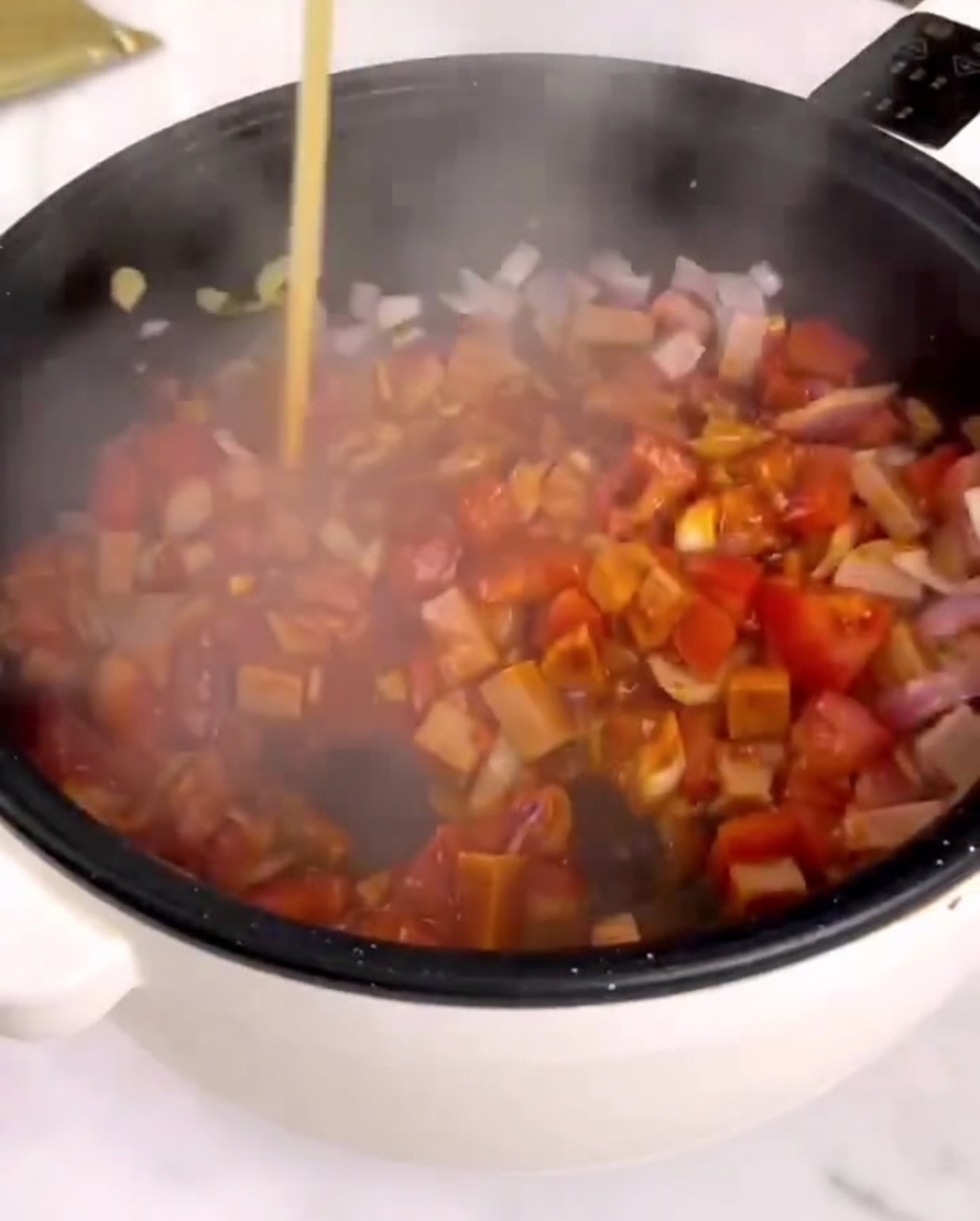 Salsa per pasta versata in una padella con verdure saltate e prosciutto.
