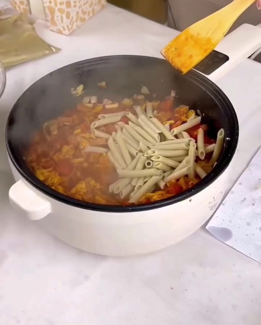 Penne sciacquate aggiunte in padella con la salsa e gli ingredienti saltati.