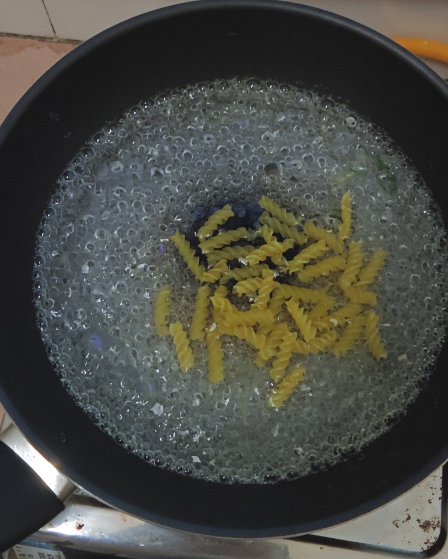 Fusilli immersi in una pentola di acqua bollente.
