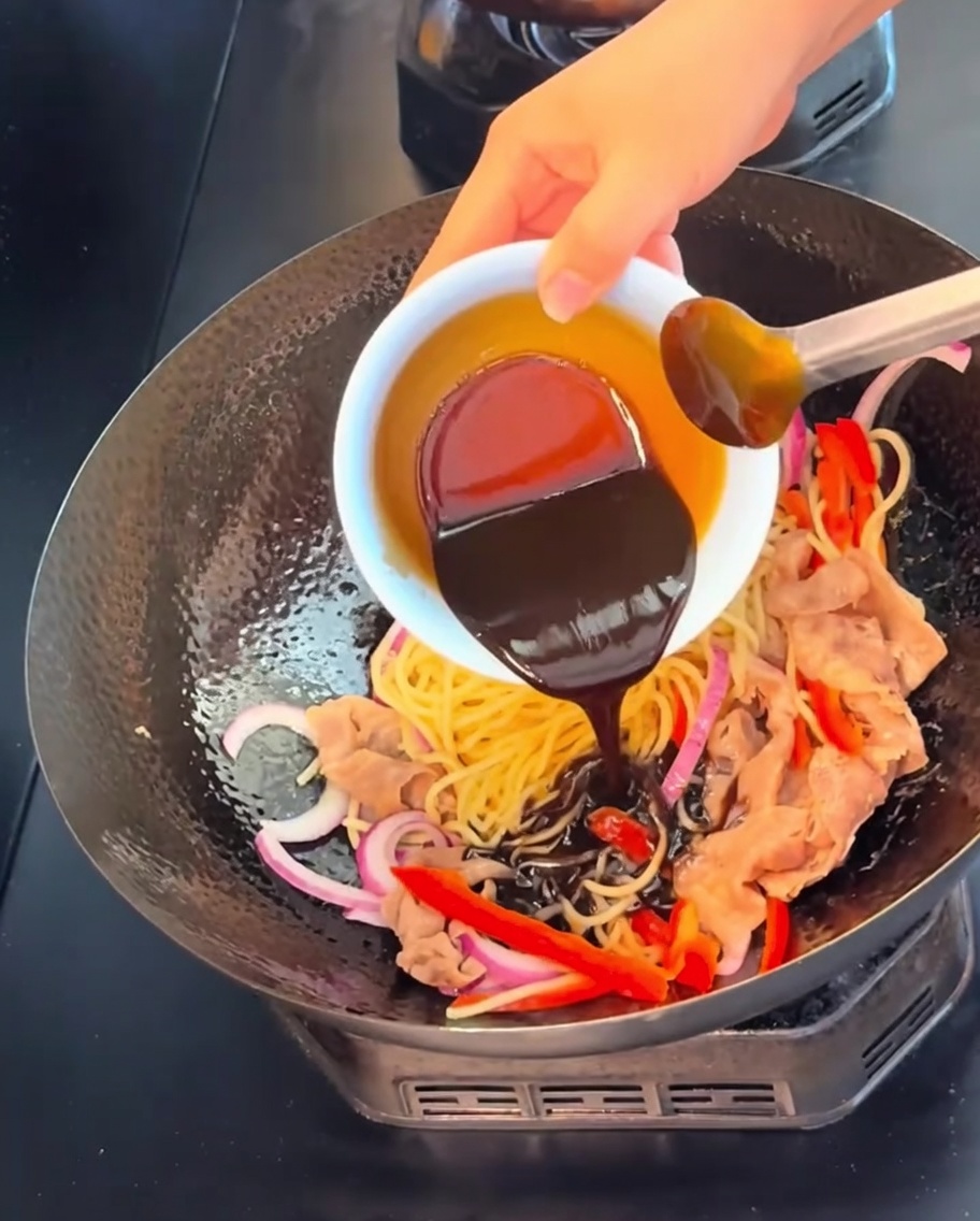 Salsa scura e ricca al pepe nero versata da una ciotolina bianca su pasta, carne e verdure.