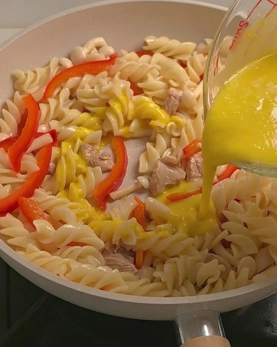 Salsa di zucca gialla e cremosa versata sui fusilli, sul pollo e sulle verdure in padella.