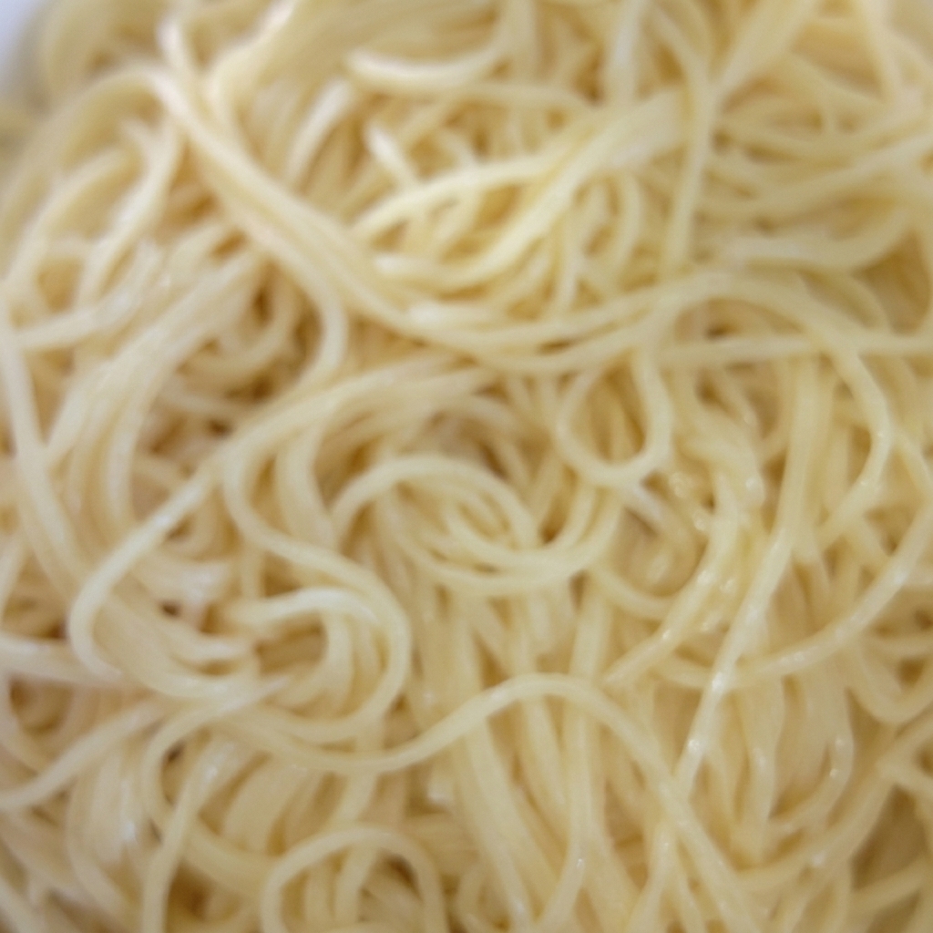 Una ciotola di spaghetti cotti conditi con olio.