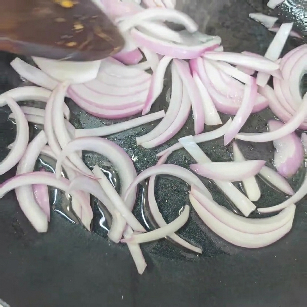 Cipolle in padella che friggono fino ad ammorbidirsi.