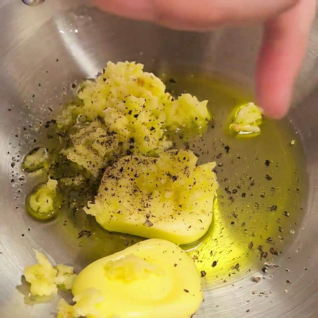 Pepe nero macinato fresco per condire la miscela di burro, aglio e olio doliva nella ciotola.