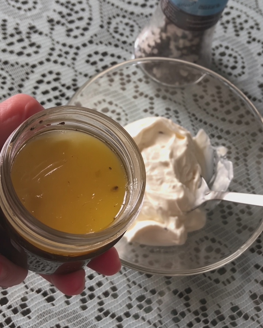 Un cucchiaio di salsa al tartufo nero aggiunto a una ciotola di panna acida.