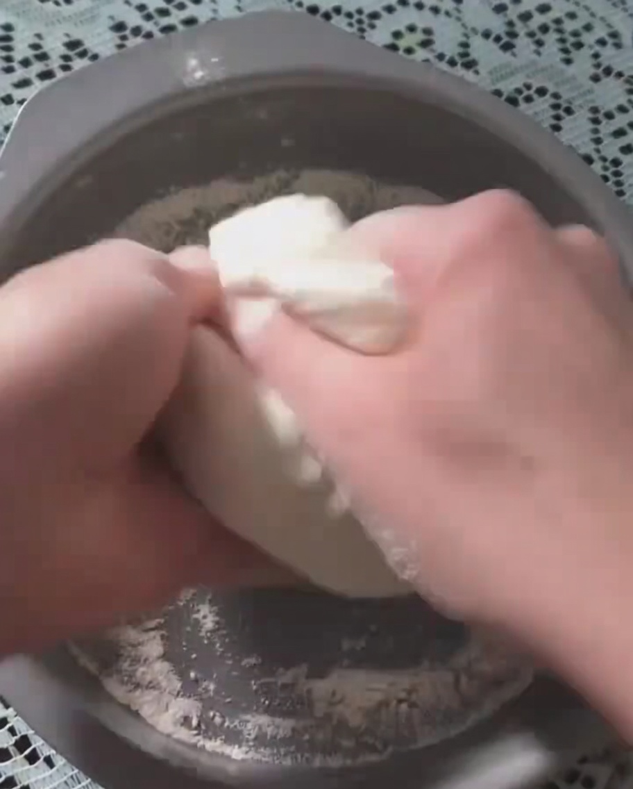 Mani che premono limpasto lievitato in una teglia circolare.