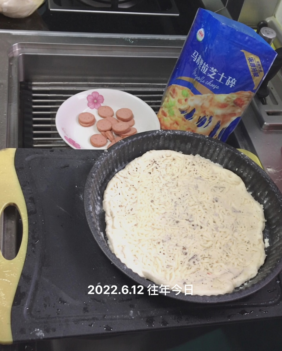 Mozzarella grattugiata sparsa sulla base della pizza.
