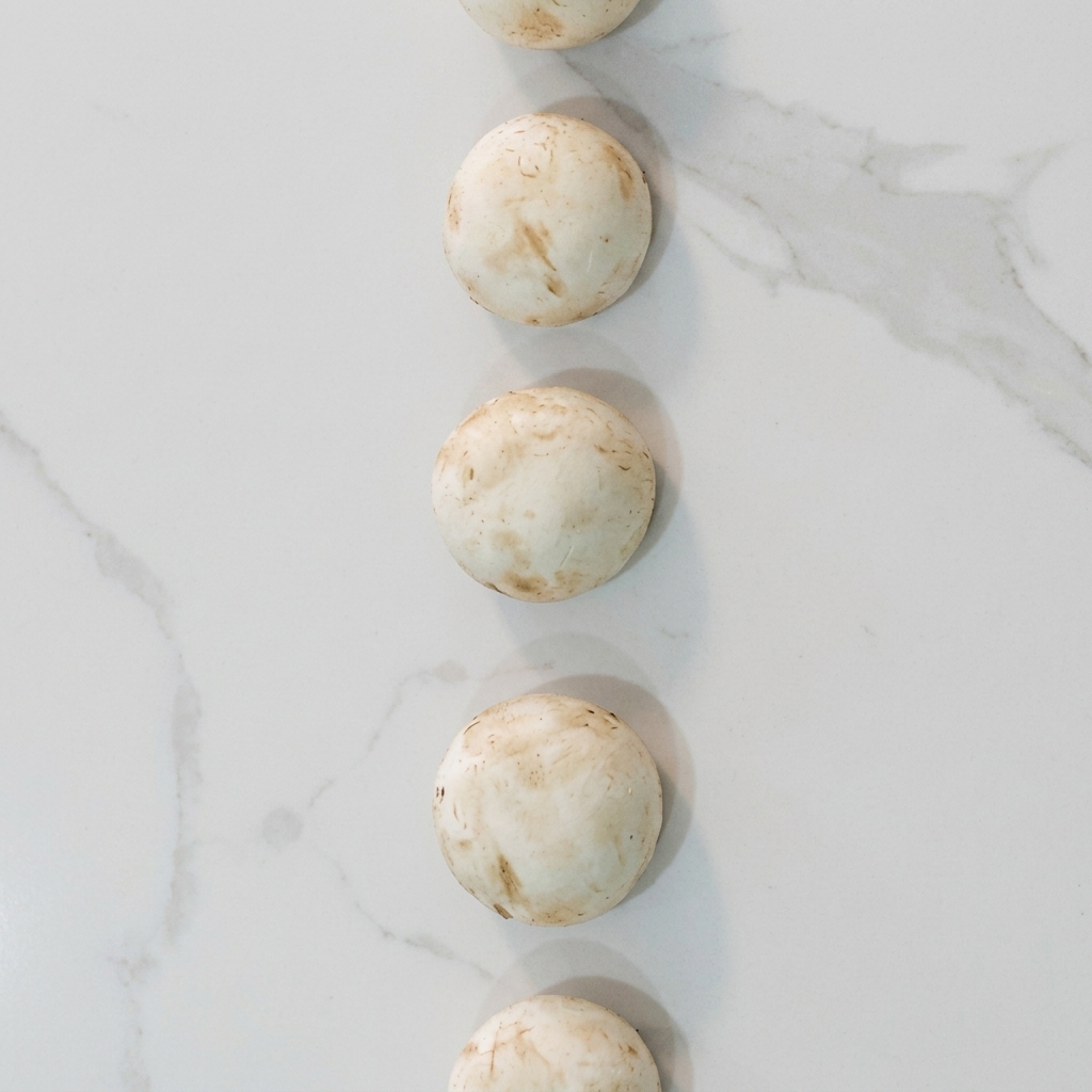 Fette di funghi prataioli che cuociono in padella con panna fino a doratura.