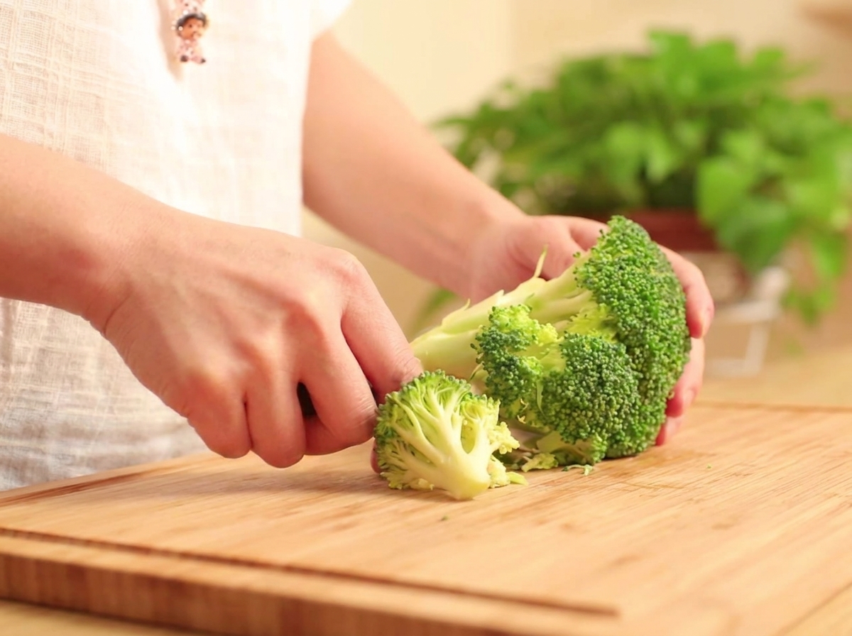 Cimette di broccoli fresche separate su un tagliere di legno.