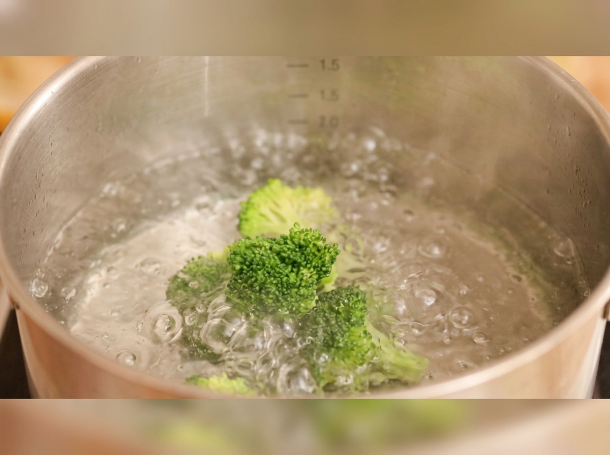 Cimette di broccoli e fette di carota che bollono in una pentola dacqua.
