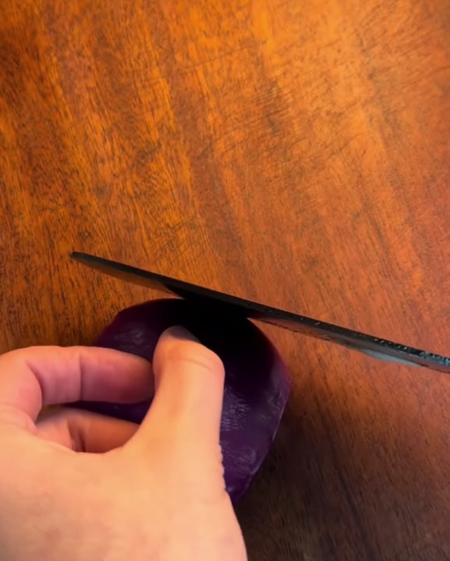 Un coltello affilato che affetta una cipolla in strisce sottili e uniformi su un tagliere di legno.