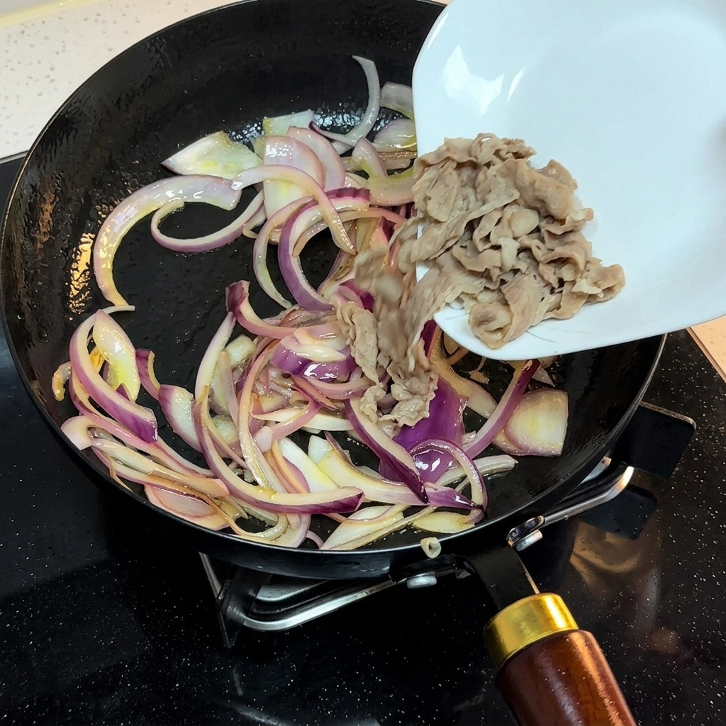 Fette di manzo sbollentate trasferite da un piatto bianco in una padella con cipolle saltate.