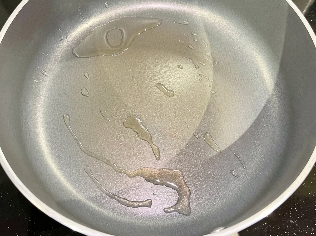 Cipolla rossa tritata che sfrigola in una padella con olio caldo.