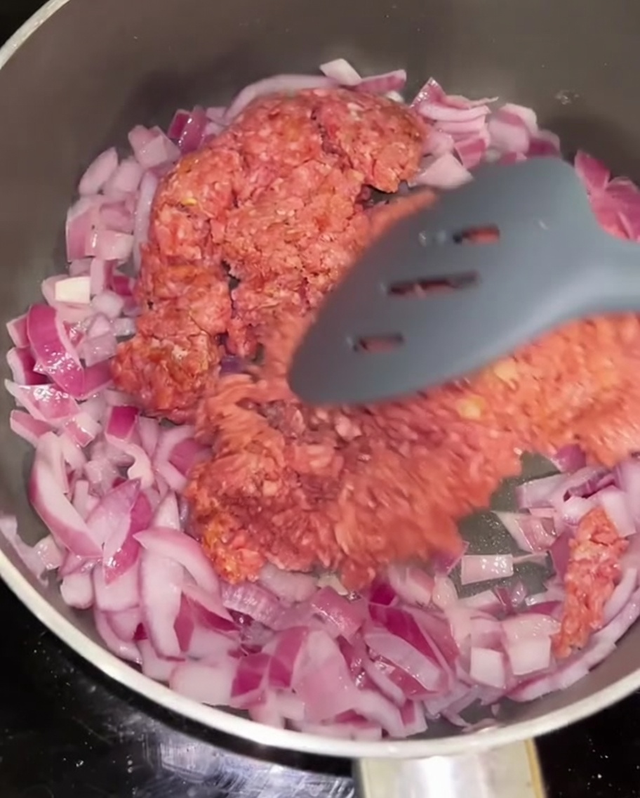 Manzo macinato che viene saltato in padella con la cipolla rossa.